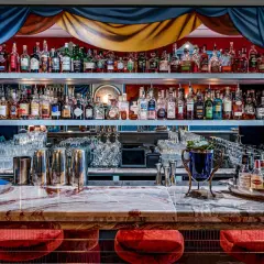 Un bar à cocktail élégant avec des étagères remplies de bouteilles d'alcool, des verres et des ustensiles de bar.