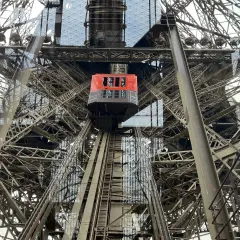 L'ascenseur rouge de la Tour Eiffel monte à travers la structure métallique complexe.