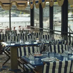 Tables dressées avec des rayures bleues et blanches, prêtes pour une "riviera fuga" sur la Seine.