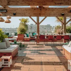 Ambiance chic et verdoyante sur le toit-terrasse du Perchoir Ménilmontant. Canapés confortables, tables dressées et vue panoramique sur Paris.
