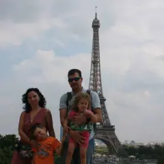 Famille souriante devant la Tour Eiffel, un classique des choses à faire à Paris avec des enfants.