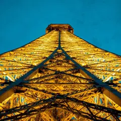 La Tour Eiffel illuminée d'une lumière dorée, comme une bougie géante, lors d'une visite nocturne à Paris.