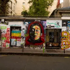 Mur couvert de graffitis colorés devant la maison Gainsbourg, avec un portrait de Serge Gainsbourg au centre.
