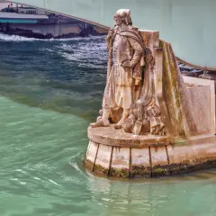 Statue de soldat sur le **pont de l'Alma**, regardant la Seine. Un bateau passe sous le pont.