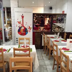Tables dressées dans un restaurant portugais. Un homme derrière le bar, une guitare colorée sur une bannière.