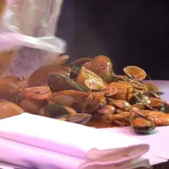 Un festin de fruits de mer à Paris : crevettes, moules et palourdes baignant dans une sauce savoureuse.