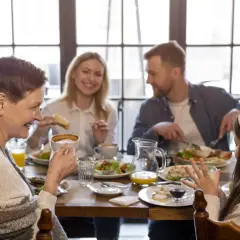 Une famille profite d'un repas joyeux dans un restaurant pour enfant. Grand-mère, parents et fille partagent un moment convivial autour d'une table garnie.