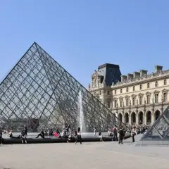 La pyramide du Louvre, un des musées ouverts le lundi, attire des visiteurs sous un ciel bleu.