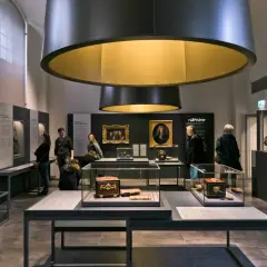 Visiteurs admirant des objets d'art et des portraits dans une exposition au musée Monnaie de Paris.