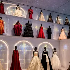 Élégantes robes de haute couture sur mannequins, une **exposition mode Paris** féerique sous un ciel étoilé.