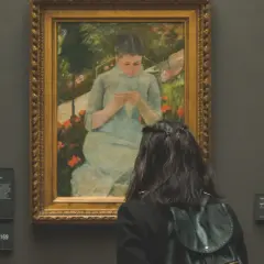Une visite au musée gratuit premier dimanche du mois. Une jeune femme admire un tableau représentant une jeune fille tricotant dans un jardin.