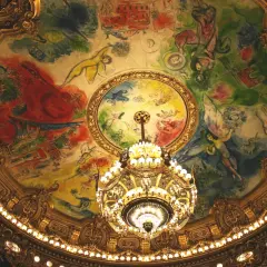 Le plafond peint de la **place de l'Opéra** est illuminé par un lustre doré. Des figures célestes dansent sur une toile colorée.