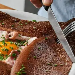 Une galette complète, garnie d'œuf, jambon et ciboulette. Une bouchée des meilleures crêpes à Paris.