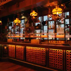 Ambiance chaleureuse d'un bar parisien, avec des lumières tamisées, des étagères remplies de bouteilles et de bibelots, évoquant un **barrio latino** à Paris.