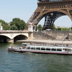 Les vedettes du Pont Neuf naviguent sur la Seine, sous la Tour Eiffel et le pont.