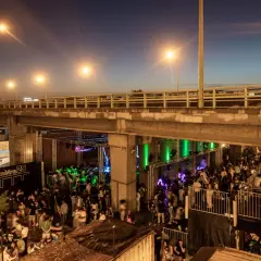 Soirée animée sous un pont, avec une foule dansant et profitant de la musique au Kilomètre 25.