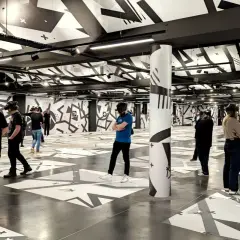 Des personnes équipées de casques VR explorent un espace immersif aux motifs graphiques noirs et blancs, une expérience unique à Eclipso Paris.