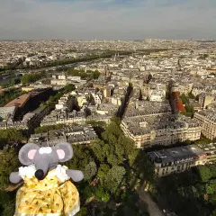 Une souris en robe jaune admire Paris depuis le sommet de la Tour Eiffel.