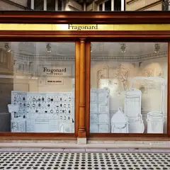 Vitrine du musée du parfum Fragonard, avec des illustrations de flacons, d'alambics et de mobilier d'apothicaire.