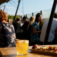 Cocktail et tapas sur une terrasse de toit à Paris, avec des gens en arrière-plan.