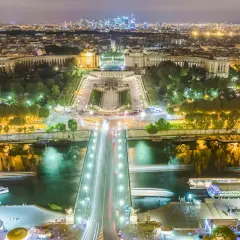 Paris la nuit, le scintillement de la Tour Eiffel se reflète sur la Seine, illuminant la ville.