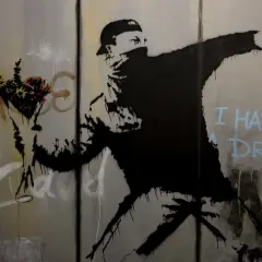 Un homme lance des fleurs, un message d'espoir du musée Banksy Paris. "I have a dream" écrit en bleu.