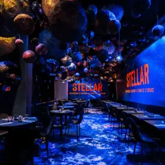 Décoration de restaurant "STELLAR" avec des planètes suspendues, évoquant un voyage **éphemère stellaire**. L'ambiance est cosmique et immersive.