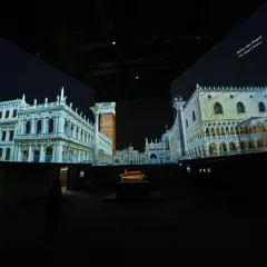 Dans un grand palais immersif, des projections vidéo recréent Venise. On y voit le Palais des Doges et d'autres édifices majestueux.