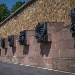 Sculptures sombres sur un mur de pierre à Mont Valérien, évoquant des figures humaines et animales dans un style dramatique.