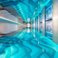Piscine intérieure luxueuse d'un spa à Paris, avec un éclairage bleu vif, des voilages blancs et une vue sur la ville.