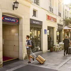 Un jeune homme avec une valise et une carte cherche que faire ce week-end à Paris, passant devant des cafés et l'entrée de la station "MINTURE".