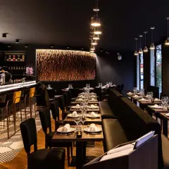 Ambiance chic d'un restaurant thaïlandais, avec un bar lumineux, des tables dressées et une décoration murale en bois.