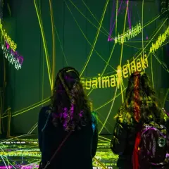 Deux personnes découvrent une exposition immersive à Paris, baignée de lumières vives et de textes projetés.