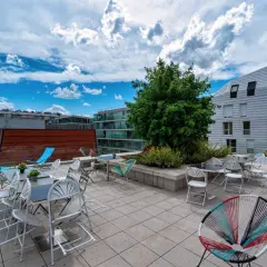 Terrasse ensoleillée avec chaises colorées et tables, un lieu idéal pour la maison de la conversation.