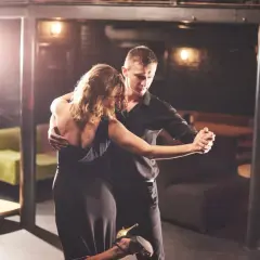 Un couple danse passionnément lors d'une soirée dansante à Paris. L'homme en chemise noire enlace la femme en robe de soirée.