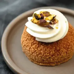 Un délice parisien : un chou craquelin garni de crème onctueuse et parsemé de pistaches concassées.