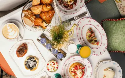 Un délicieux brunch parisien avec viennoiseries, tartines, pancakes aux fraises, et une tasse de café.