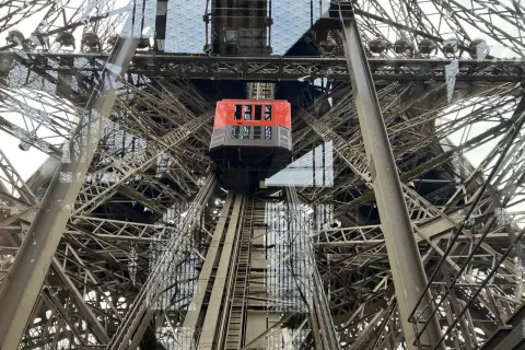 L'ascenseur rouge de la Tour Eiffel monte à travers la structure métallique complexe.