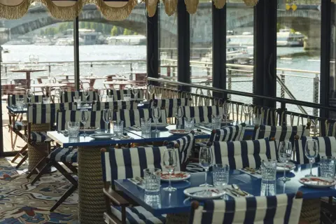 Tables dressées avec des rayures bleues et blanches, prêtes pour une "riviera fuga" sur la Seine.
