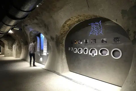 Visite du musée des égouts de Paris. Un visiteur observe une exposition sur le réseau d'assainissement, avec une carte lumineuse et des maquettes.