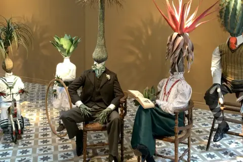 Mannequins aux têtes végétales dans l'espace Monte Cristo. Un enfant sur un tricycle, un couple lisant, un autre debout.