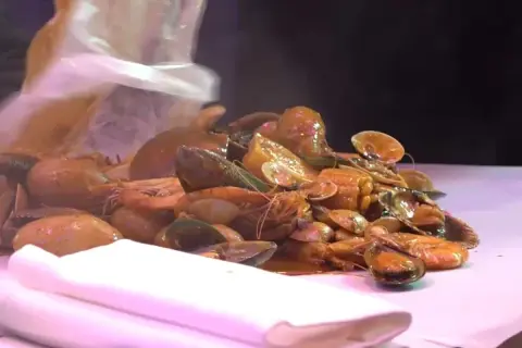 Un festin de fruits de mer à Paris : crevettes, moules et palourdes baignant dans une sauce savoureuse.