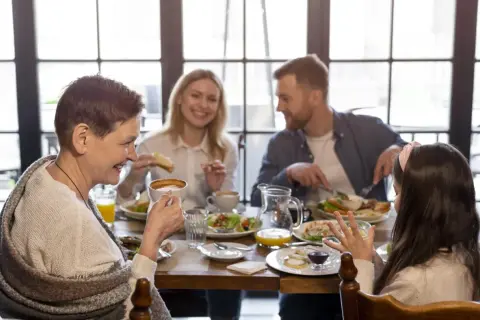 Une famille profite d'un repas joyeux dans un restaurant pour enfant. Grand-mère, parents et fille partagent un moment convivial autour d'une table garnie.