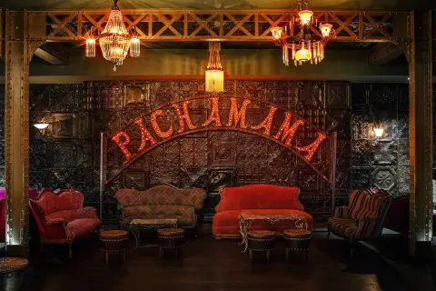 Ambiance feutrée au Pachamama Paris. Canapés vintage, luminaires scintillants et enseigne lumineuse pour un avis mémorable.