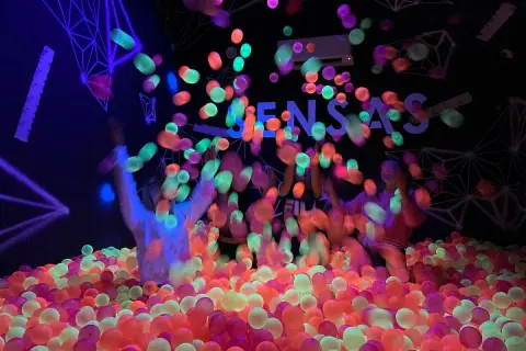 Des balles fluorescentes pleuvent sur des enfants dans une piscine à balles colorée. Une expérience sensas Paris inoubliable.