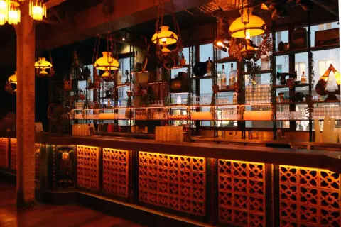 Ambiance chaleureuse d'un bar parisien, avec des lumières tamisées, des étagères remplies de bouteilles et de bibelots, évoquant un **barrio latino** à Paris.