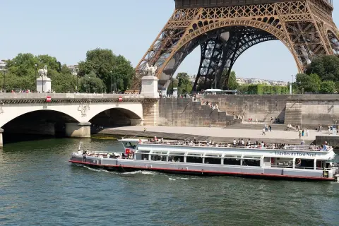 Les vedettes du Pont Neuf naviguent sur la Seine, sous la Tour Eiffel et le pont.