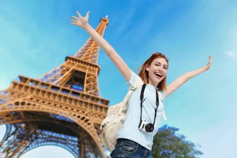 Joyeuse touriste avec appareil photo devant la Tour Eiffel. Un bon plan Paris pour des souvenirs inoubliables !