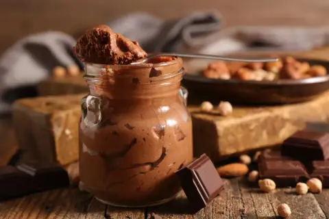 Une cuillère de mousse au chocolat parisienne, onctueuse et gourmande, sur fond de chocolat noir et noisettes.