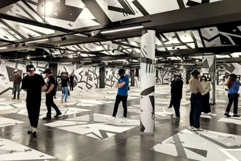 Des personnes équipées de casques VR explorent un espace immersif aux motifs graphiques noirs et blancs, une expérience unique à Eclipso Paris.